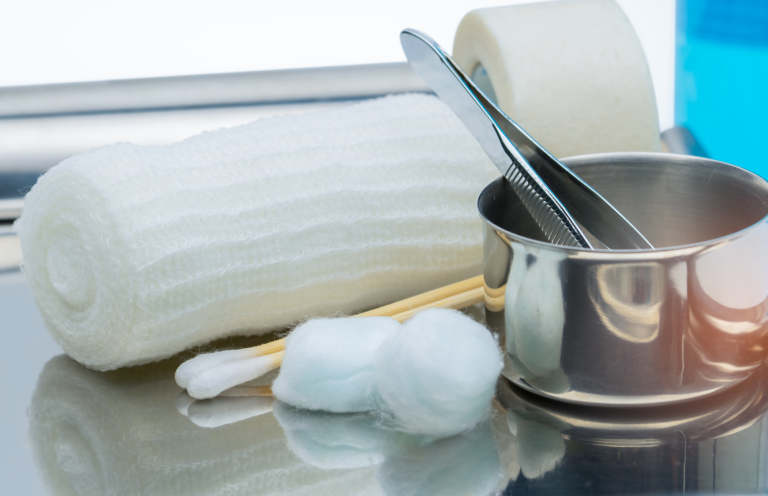 Introduction to Wound Care First aid supplies including bandages, cotton balls, and metal tools on a surface.