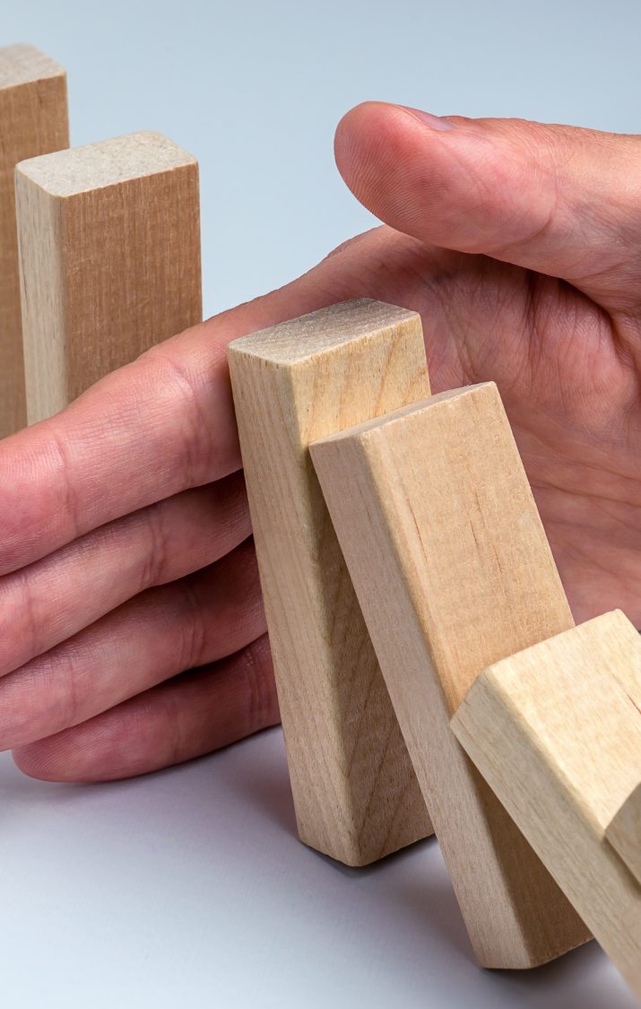 Falls Prevention Training A hand supports a falling wooden block among upright blocks.