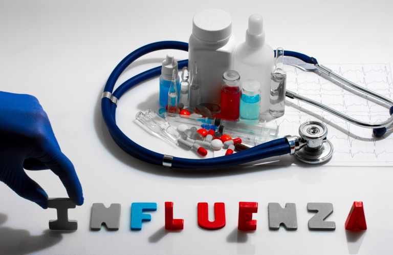 Influenza Update A stethoscope, medicine bottles, and letters spelling "INFLUENZA" on a table.