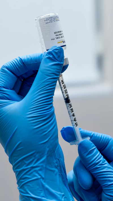 Vaccination A gloved hand holds a syringe ready for vaccination with a vial in the background.